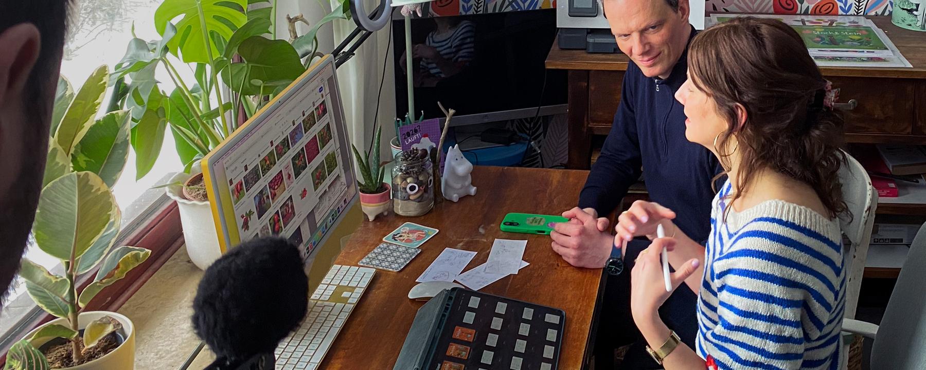 Der Journalist Florian Neuhann und die Kinderbuchillustratorin Anne Behl sitzen nebeneinander an einem Schreibtisch vor einem Fenster.