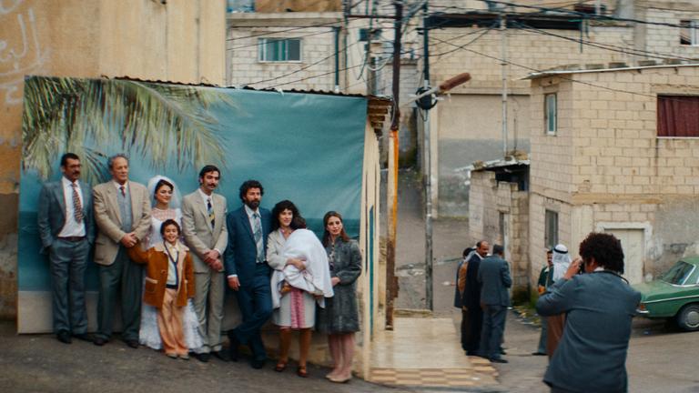 Ein Fotograf fotografiert eine Hochzeitsgesellschaft, die sich für das Bild in Reihen hintereinander aufgestellt hat.
