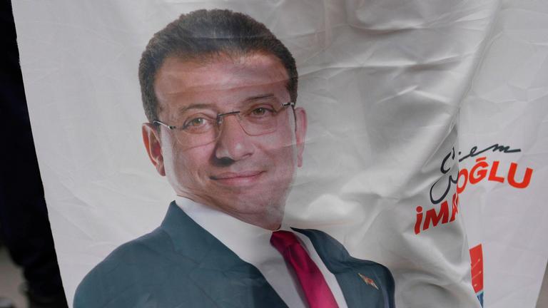 Menschen versammeln sich mit einem Transparent, auf dem ein Foto des Istanbuler Bürgermeisters Ekrem Imamoglu abgebildet ist, um gegen seine Verhaftung zu protestieren.