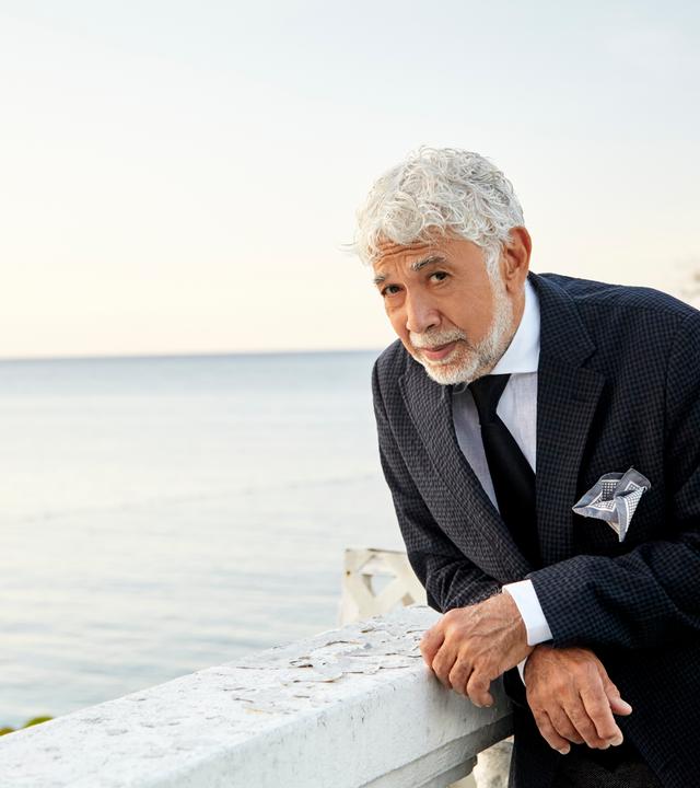 Der jamaikanische Jazzpianist Monty Alexander in mediterranem Flair, auf eine Balustrade gestützt, im Anzug. Dahinter das Meer, er schaut etwas verschmitzt-fragend in die Kamera.