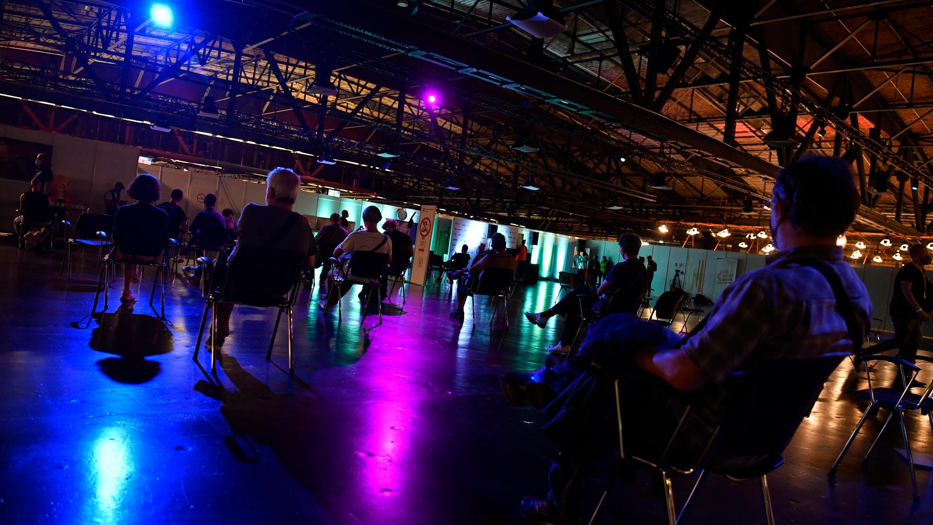 Menschen stehen bei der 1. Langen Nacht des Impfens am Impfzentrum Arena in Treptow an. Das Impfangebot des nächtlichen Impfens mit Musik richtet sich auch an Jugendliche ab 16 Jahren. Diese müssen unter anderem den von den Erziehungsberechtigten unterschriebenen Einwilligungsbogen vorlegen.