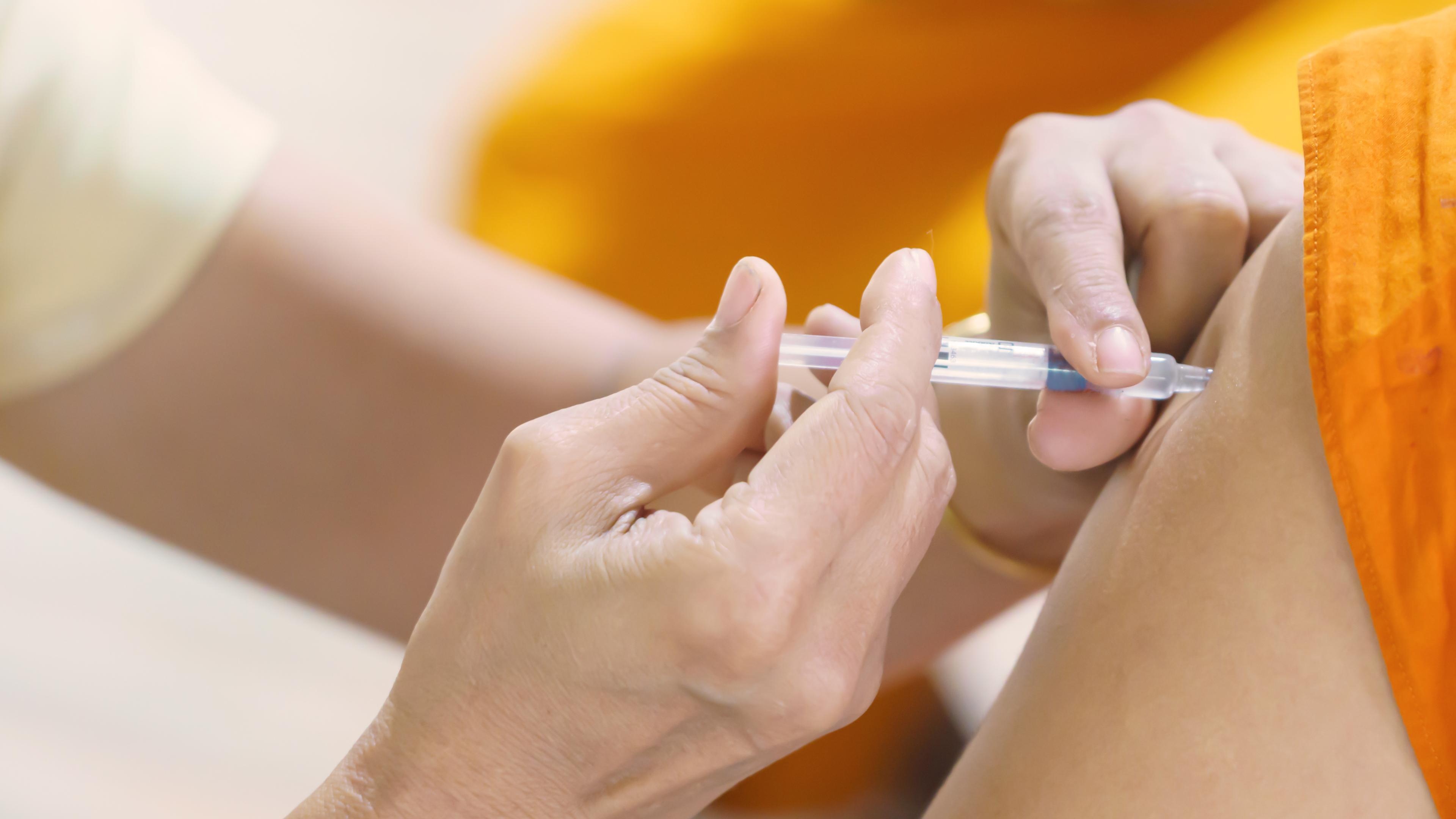 Ein Patient wird mit der Spritze im Arm geimpft.