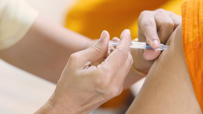 Ein Patient wird mit der Spritze im Arm geimpft.