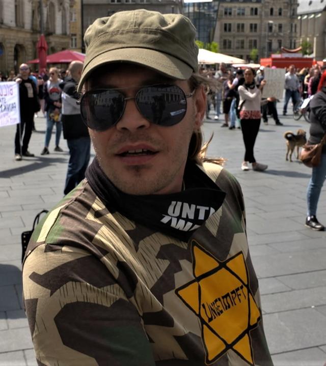 Mann mit Judenstern auf dem Shirt und Aufschrift "ungeimpft" auf Demo gegen Corona-Maßnahmen