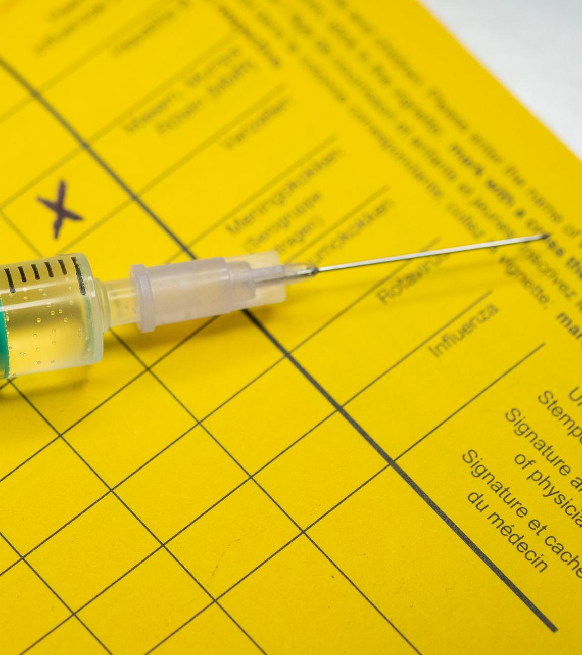 Eine Spritze liegt auf einem Impfpass. (Symbolbild)