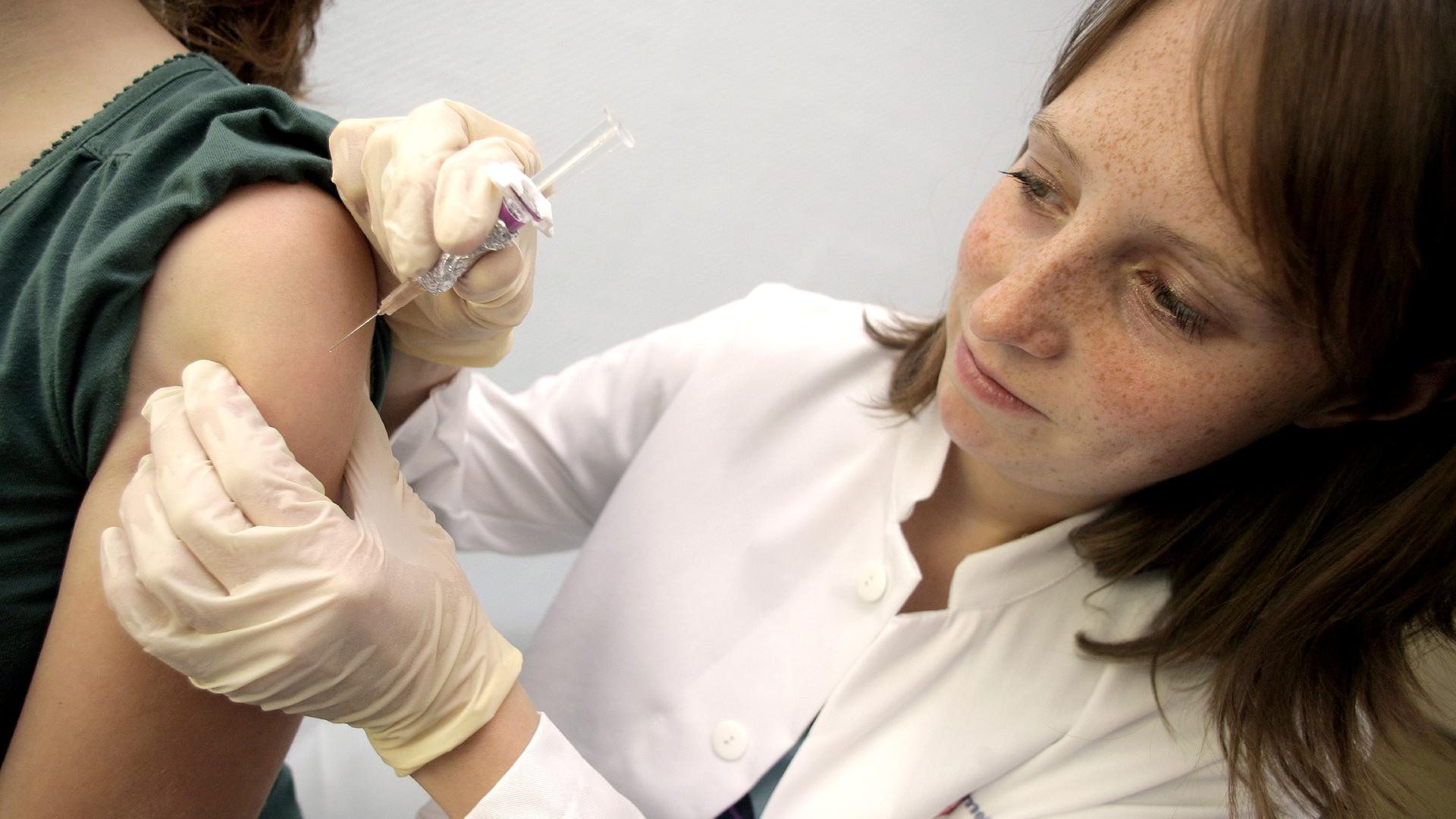 Ärztin impft ein junges Mädchen