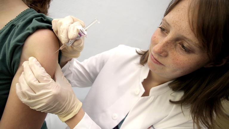 Ärztin impft ein junges Mädchen