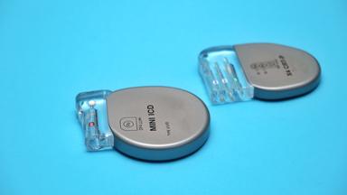 Zwei implantierbare Defibrillatoren liegen auf einer blauben Oberfläche.