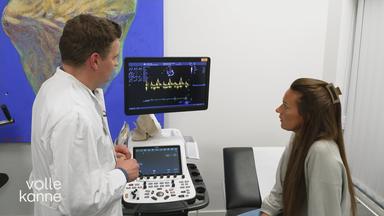 Patientin und Arzt stehen vor einem EKG