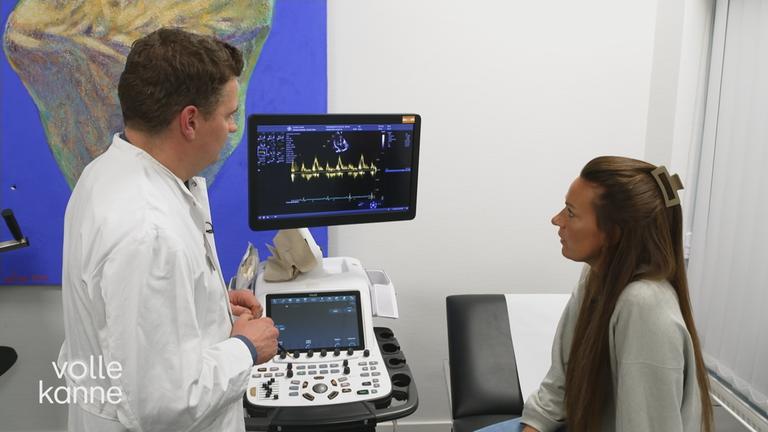 Patientin und Arzt stehen vor einem EKG