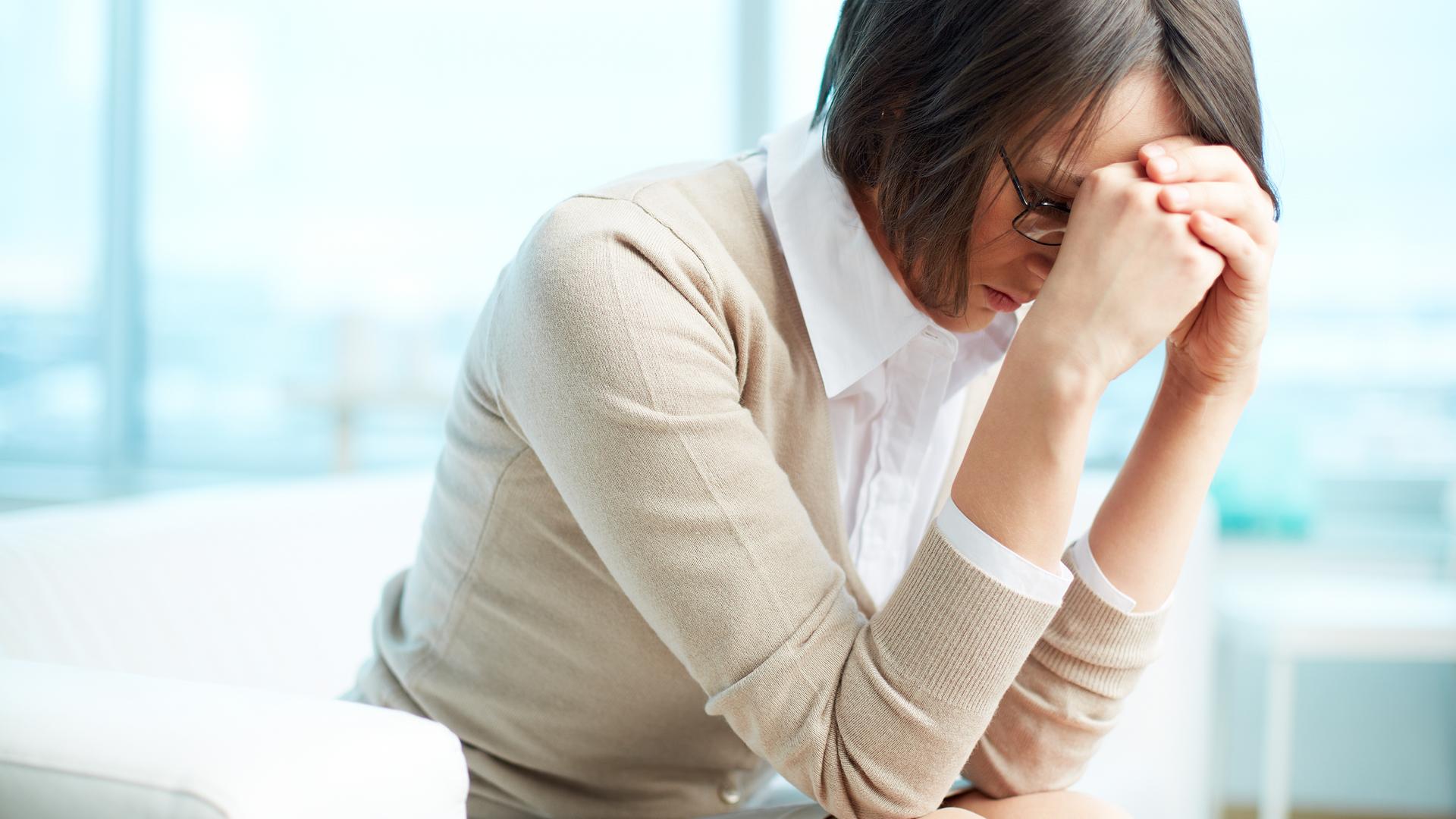 Eine Frau stützt verzweifelt den Kopf in die Hände.