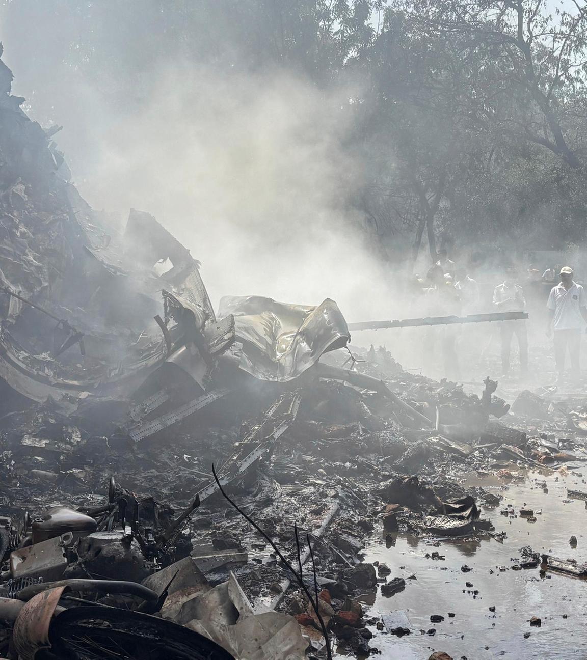 12.06.2025, Indien, Ahmedabad: Feuerwehrleute arbeiten an der Absturzstelle eines Flugzeugs in der nordwestlichen Stadt Ahmedabad im indischen Bundesstaat Gujarat