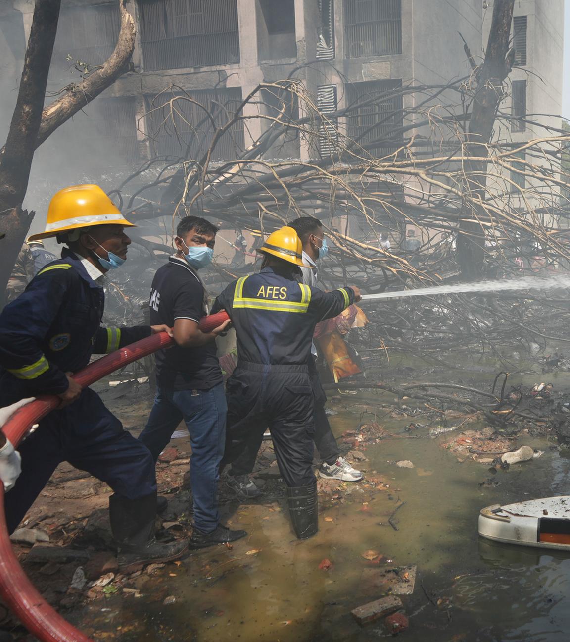 12.06.2025, Indien, Ahmedabad: Feuerwehrleute arbeiten an der Absturzstelle eines Flugzeugs in der nordwestlichen Stadt Ahmedabad im indischen Bundesstaat Gujarat
