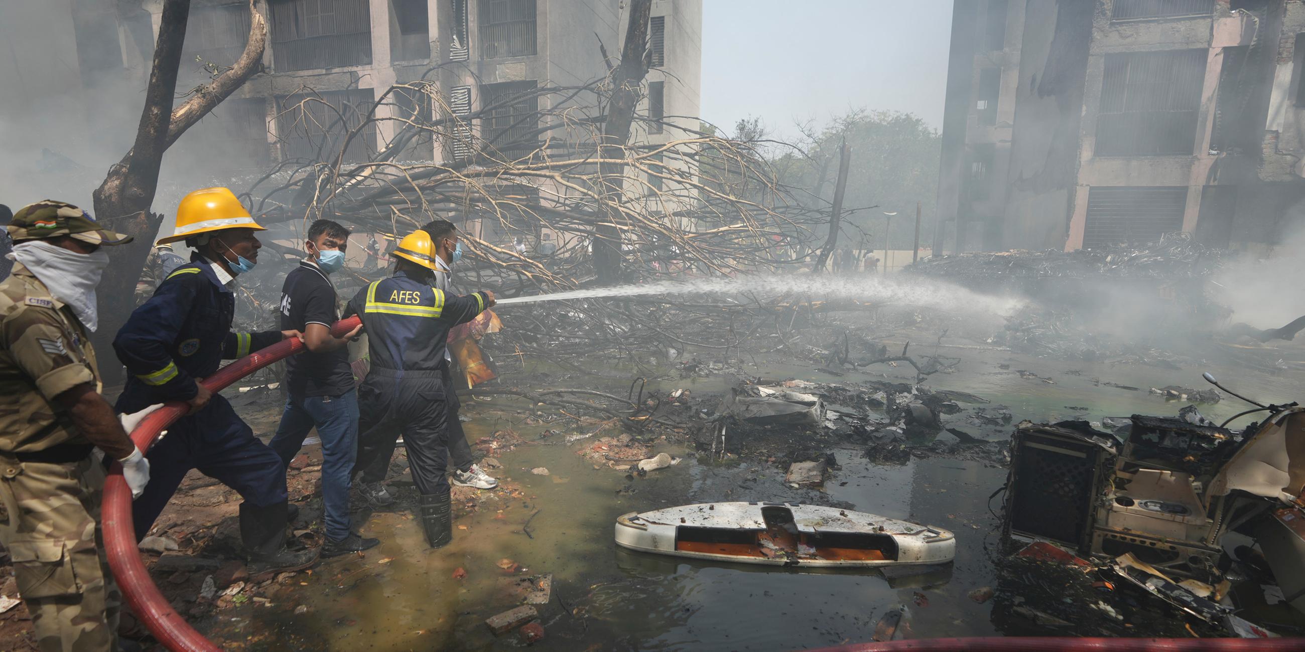 12.06.2025, Indien, Ahmedabad: Feuerwehrleute arbeiten an der Absturzstelle eines Flugzeugs in der nordwestlichen Stadt Ahmedabad im indischen Bundesstaat Gujarat
