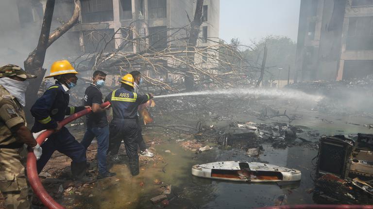 12.06.2025, Indien, Ahmedabad: Feuerwehrleute arbeiten an der Absturzstelle eines Flugzeugs in der nordwestlichen Stadt Ahmedabad im indischen Bundesstaat Gujarat
