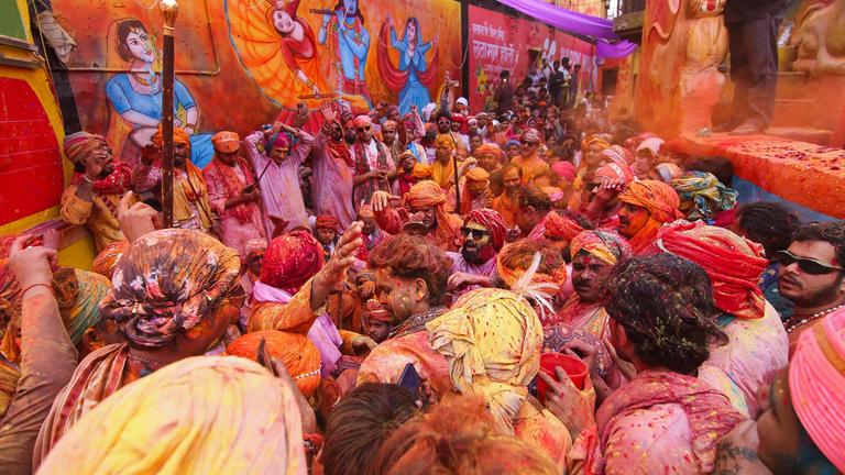 Feiernde zelebrieren Lathmar Holi, das hinduistische Frühlingsfest der Farben, neben einem Wandgemälde von Lord Krishna in Barsana.