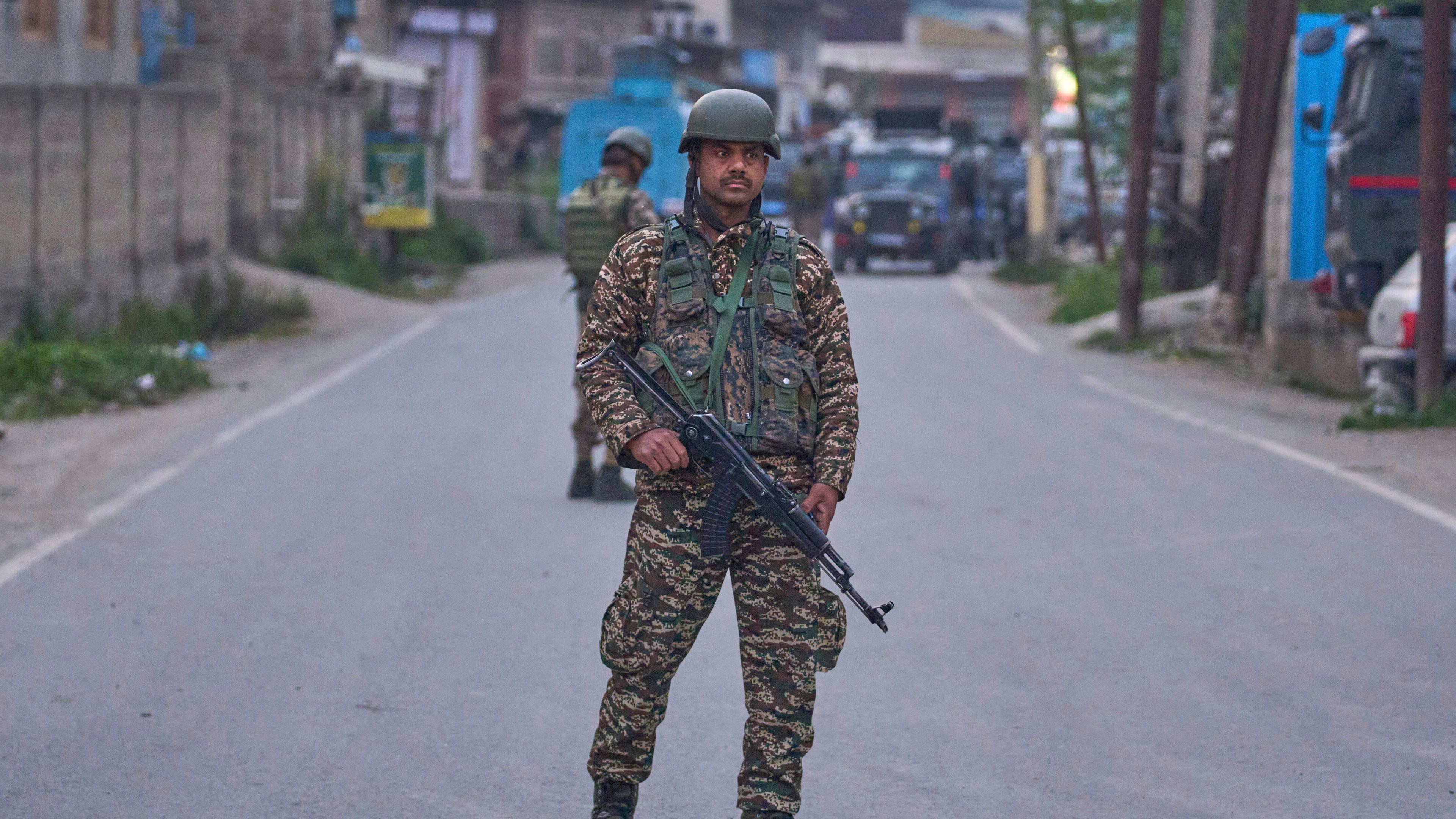 Soldat mit Maschinengewehr und in Uniform steht auf Straße.