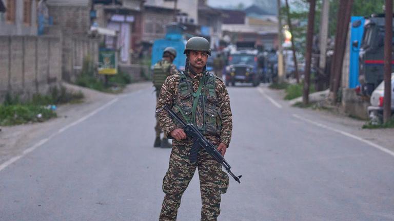 Soldat mit Maschinengewehr und in Uniform steht auf Straße.