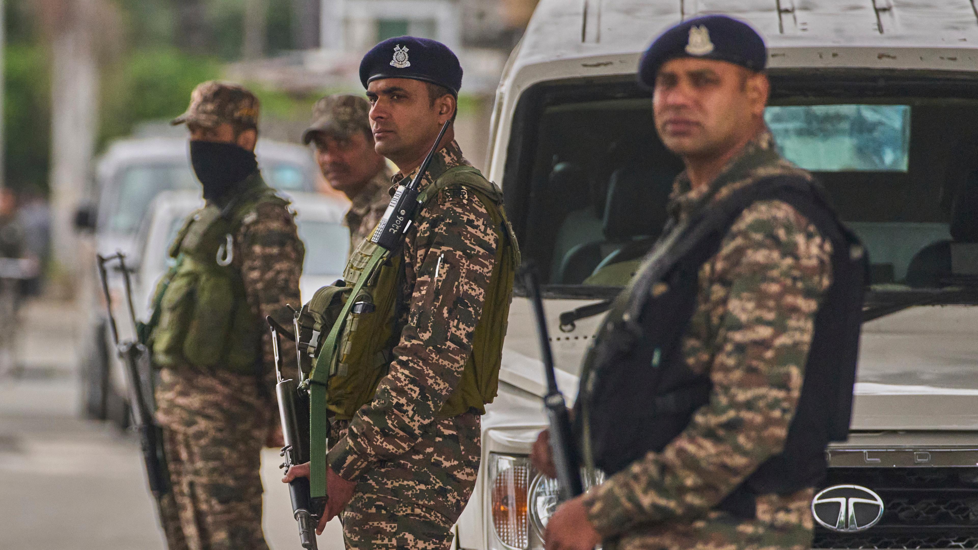 Indische paramilitärische Soldaten stehen Wache an einem provisorischen Kontrollpunkt auf einer Straße.