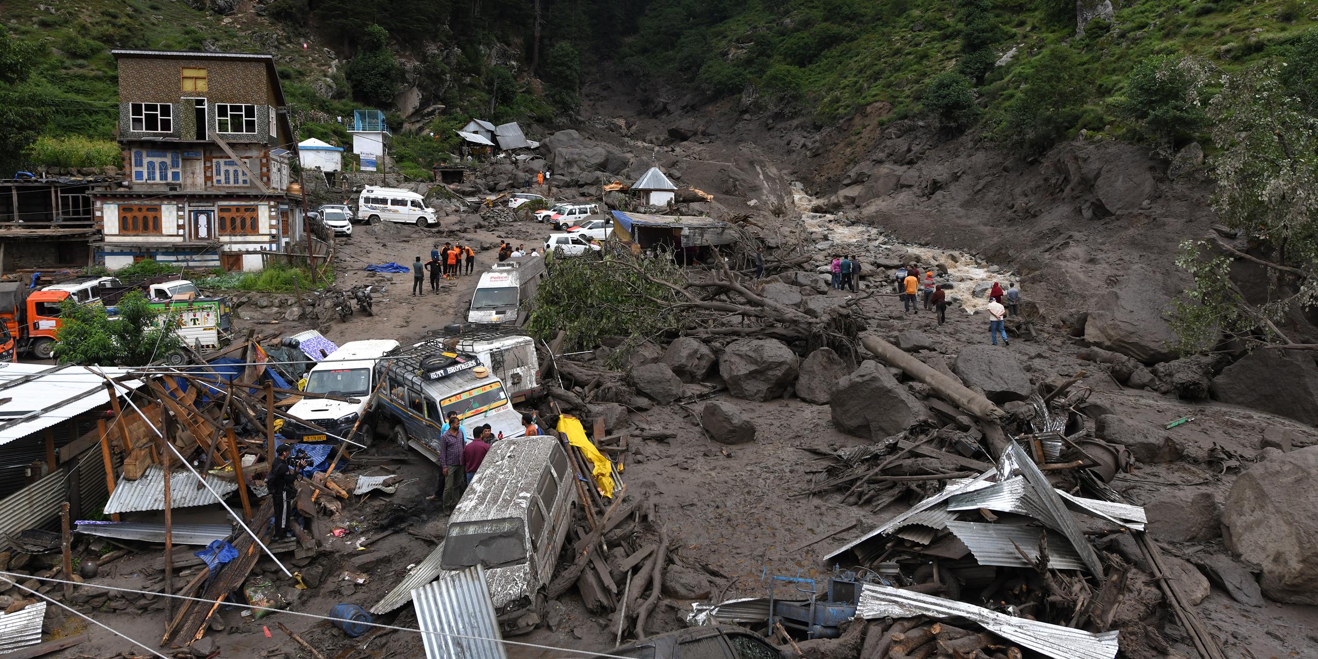 15.08.2025, Indien, Kishtwar: Rettungskräfte suchen zwischen Felsen und beschädigten Fahrzeugen nach Überlebenden und Opfern.