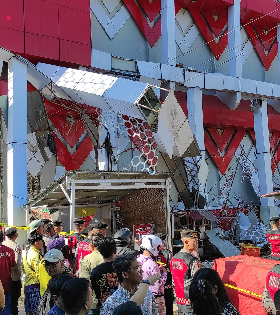 Schaulustige versammeln sich, während Polizeibeamte ein beschädigtes Gebäude nach einem Erdbeben in Manado, Nordsulawesi, Indonesien, inspizieren.