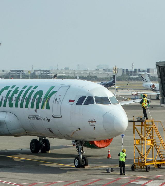 Mitarbeiter reinigen ein Flugzeug, nachdem der Flugbetrieb infolge des Ausbruchs des Vulkans Anak Krakatau eingestellt worden war