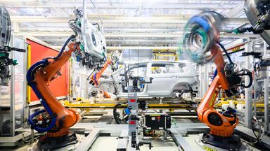 Niedersachsen, Wolfsburg: Roboter montieren im VW Stammwerk im Karosseriebau Türen an einen Neuwagen Volkswagen.