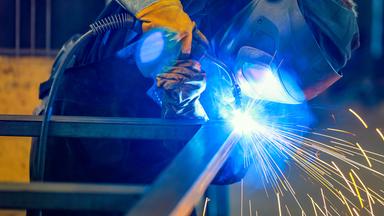 Ein Industrieschweisser schweisst ein Werkstueck.