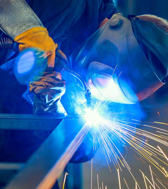 Ein Industrieschweisser schweisst ein Werkstueck.