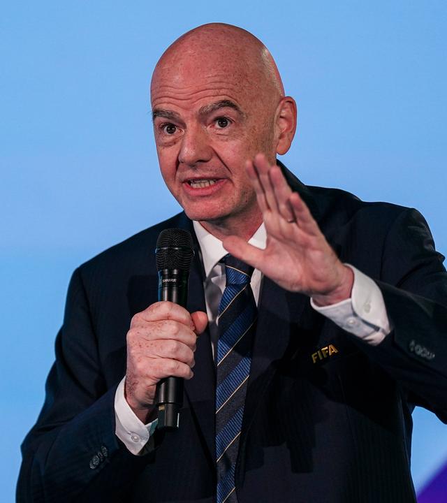 FIFA-Präsident Gianni Infantino hält in der Zentrale des Verbandes in Zürich eine Rede und hebt dabei die linke Hand. In der rechten Hand hält er ein Mikrofon.
