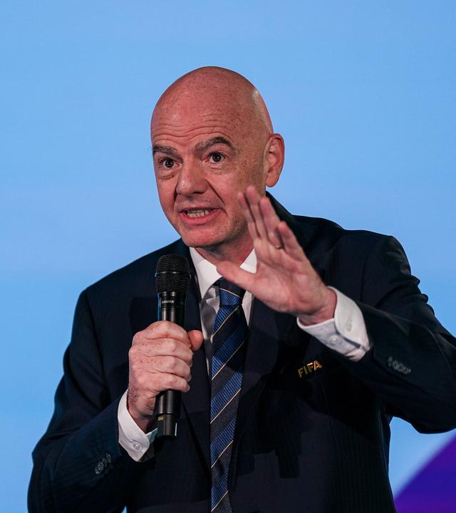 FIFA-Präsident Gianni Infantino hält in der Zentrale des Verbandes in Zürich eine Rede und hebt dabei die linke Hand. In der rechten Hand hält er ein Mikrofon.