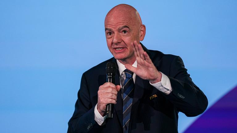 FIFA-Präsident Gianni Infantino hält in der Zentrale des Verbandes in Zürich eine Rede und hebt dabei die linke Hand. In der rechten Hand hält er ein Mikrofon.