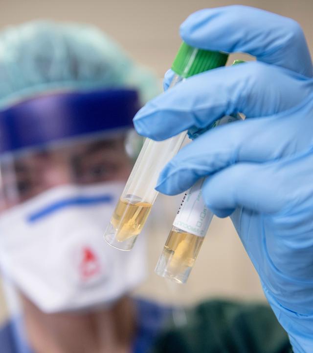 Eine Krankenschwester betrachtet zwei Abstrichröhrchen.