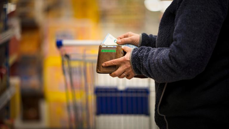 Frau zählt im Supermarkt ihr Geld