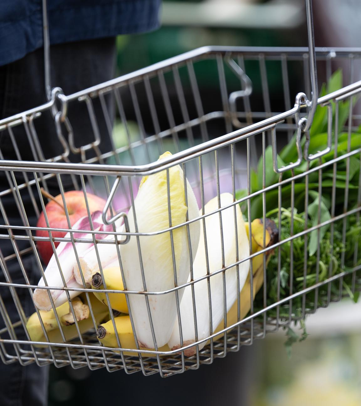 Sachsen, Dresden: Ein Mann trägt auf einem Wochenmarkt seine Einkäufe in einem Korb.