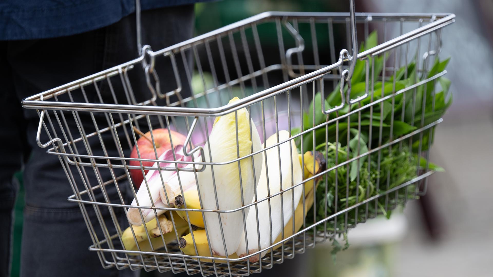 Sachsen, Dresden: Ein Mann trägt auf einem Wochenmarkt seine Einkäufe in einem Korb.