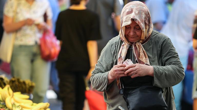 Symbolbild: Eine Frau zählt Geld auf dem Markt