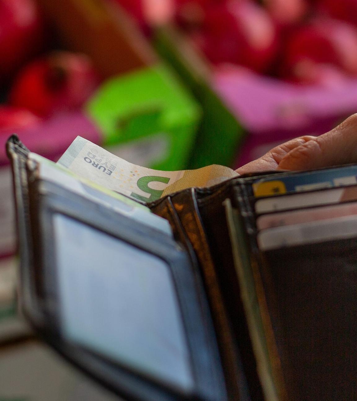Eine Frau holt einen Geldschein ihrem Portemonnaie. Symbolbild