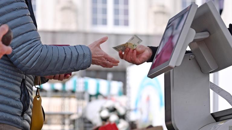 Eine Frau erhält Rückgeld an einem Marktstand auf dem Leipziger Markt