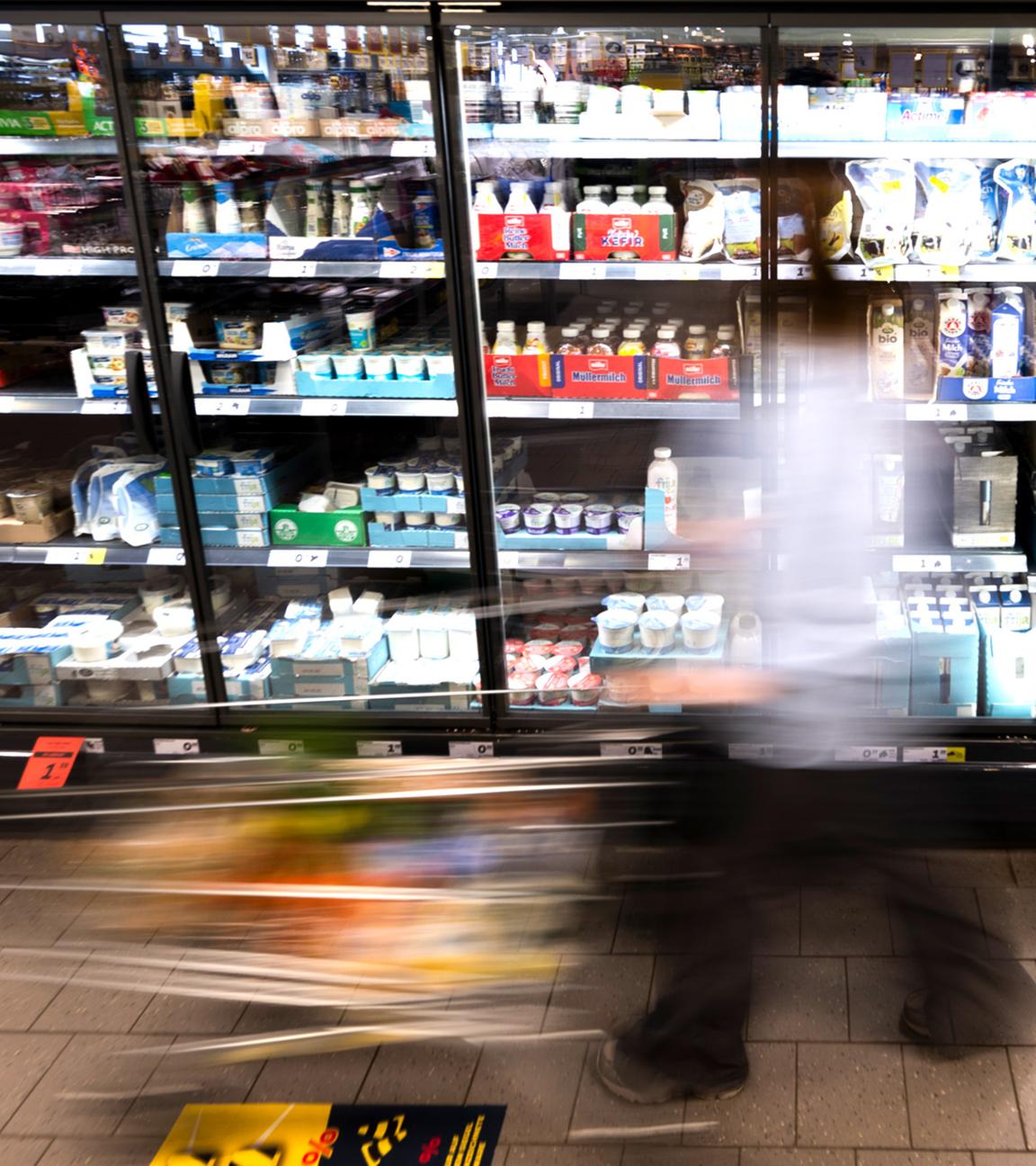  Eine Frau fährt mit ihrem Einkaufswagen vor dem Kühlregal eines Supermarkts. (Symbolfoto)