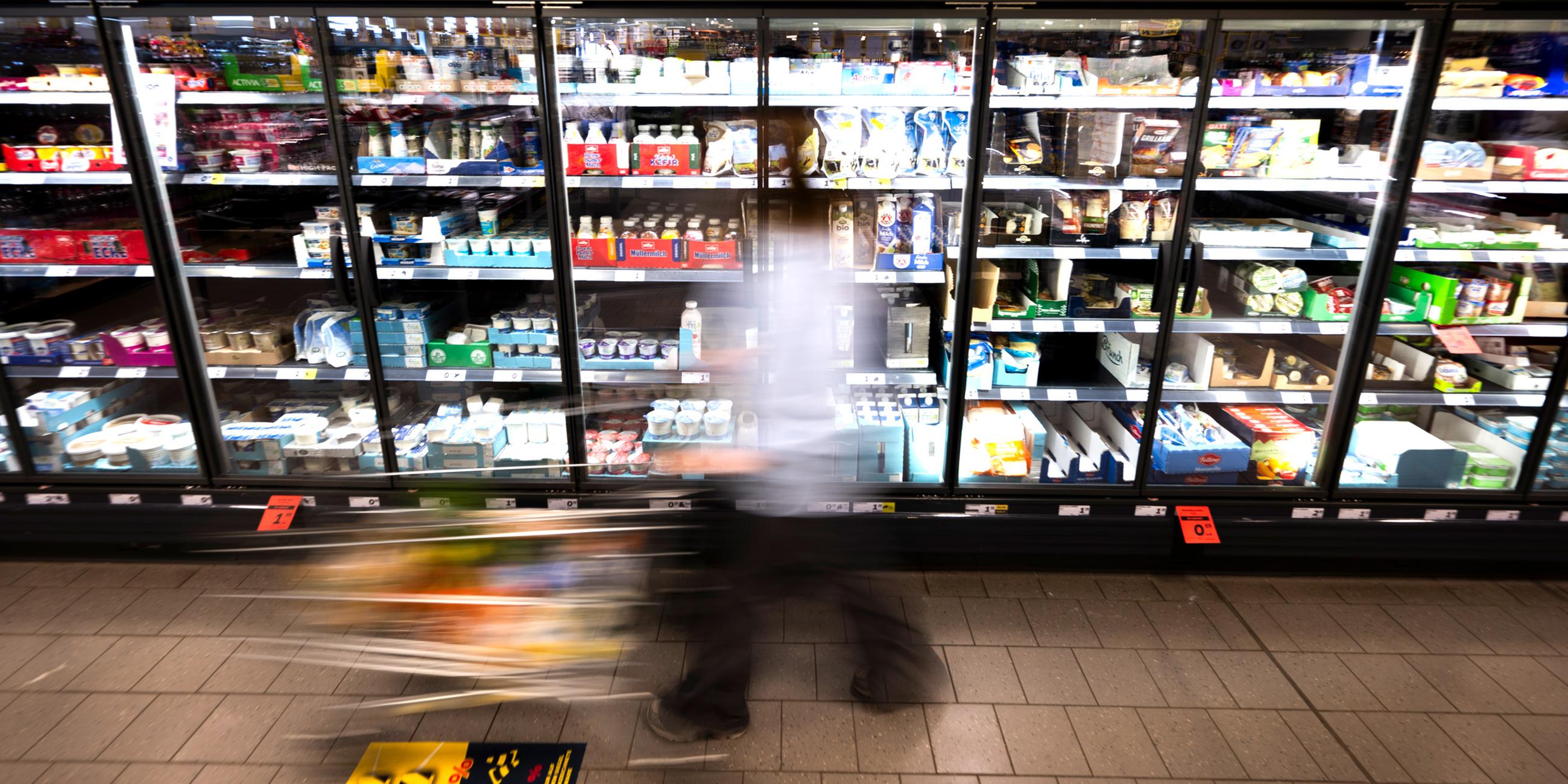  Eine Frau fährt mit ihrem Einkaufswagen vor dem Kühlregal eines Supermarkts. (Symbolfoto)