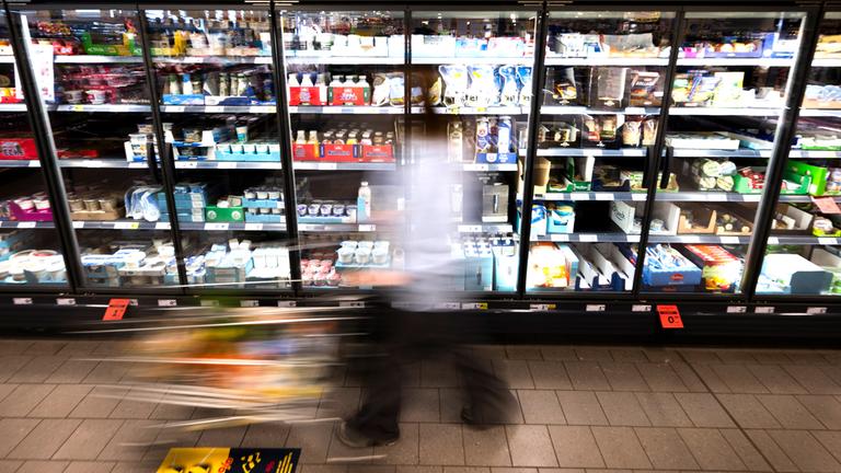  Eine Frau fährt mit ihrem Einkaufswagen vor dem Kühlregal eines Supermarkts. (Symbolfoto)