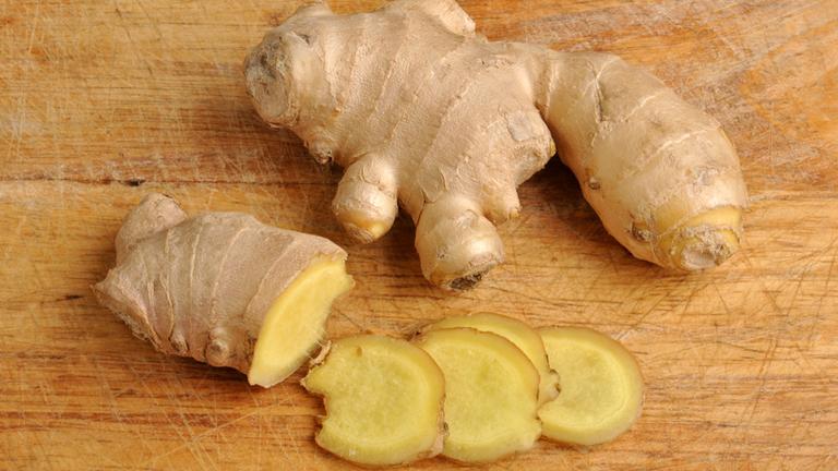 Ingwer liegt auf einem Schneidbrett und wurde zum Teil aufgeschnitten