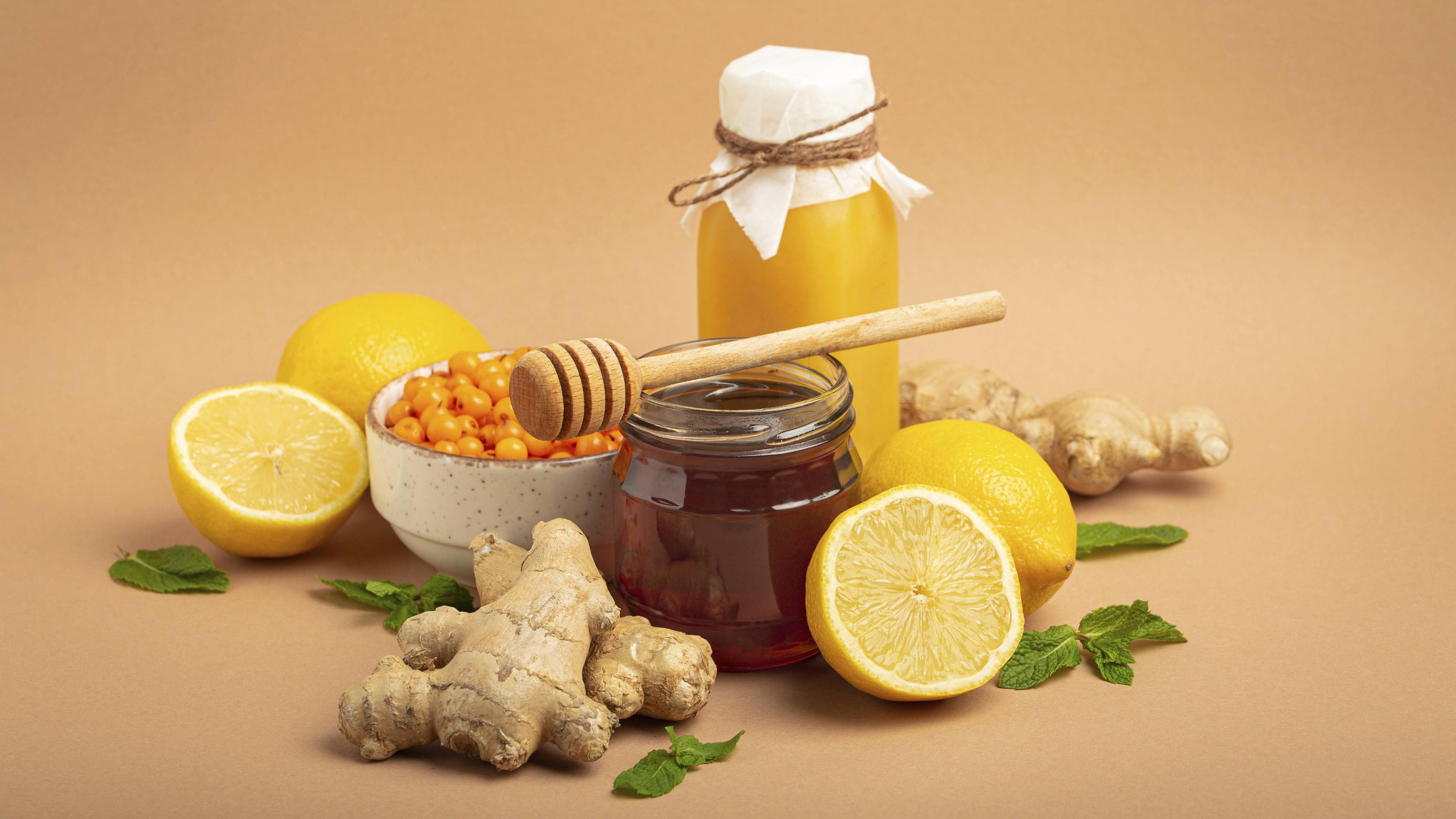 Lebensmittel zur Stimulation des Immunsystems, Sanddornbeeren, Zitronen, Minze, Ingwer, Honig im Glasgefäß.