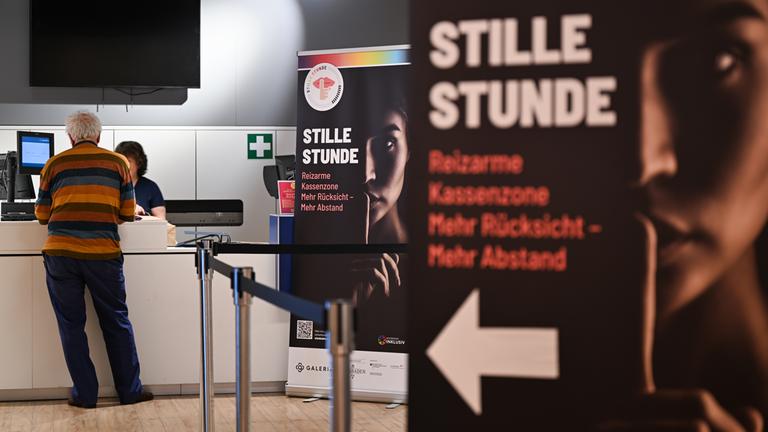 Plakate der Initiative "Stille Stunde" sind vor einer Kassenzone des Kaufhauses Galeria in Wiesbaden aufgestellt. 