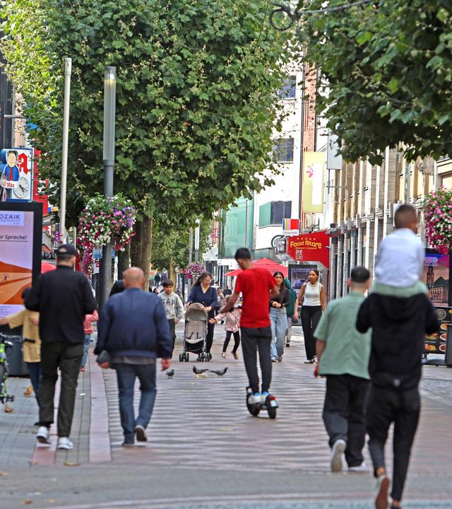 Belebte Einkaufsstraße mit zahlreichen Passanten in einer deutschen Innenstadt.
