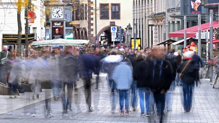 Zahlreiche Passanten gehen durch die Leipziger Innenstadt. Ihre Umrisse sind verschwommen, man erkennt keine Gesichter oder Personen.