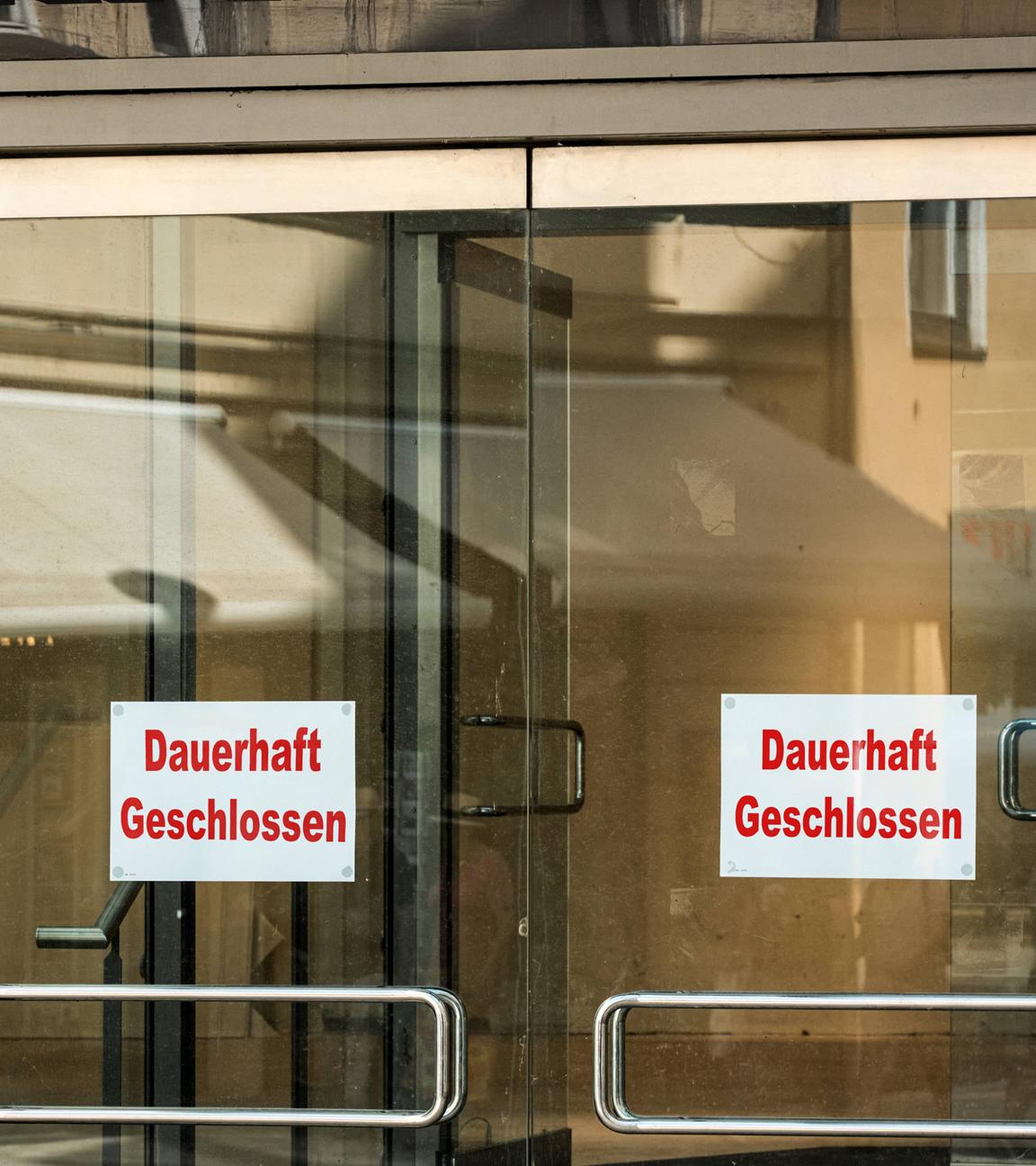 Ein Schild mit der Aufschrift "Dauerhaft Geschlossen" an einer Glastür