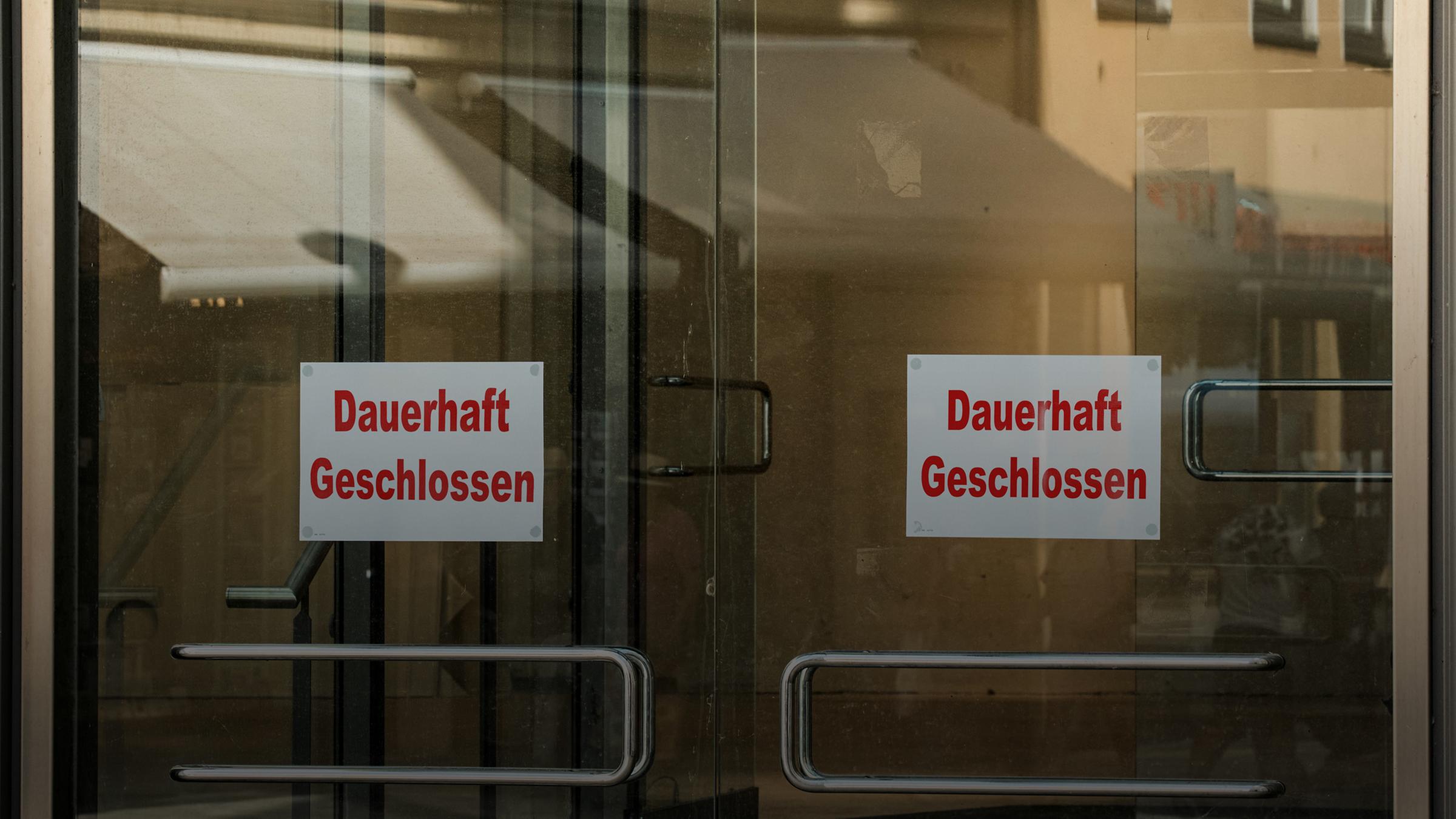 Ein Schild mit der Aufschrift "Dauerhaft Geschlossen" an einer Glastür