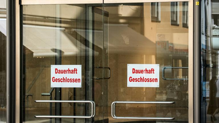 Ein Schild mit der Aufschrift "Dauerhaft Geschlossen" an einer Glastür